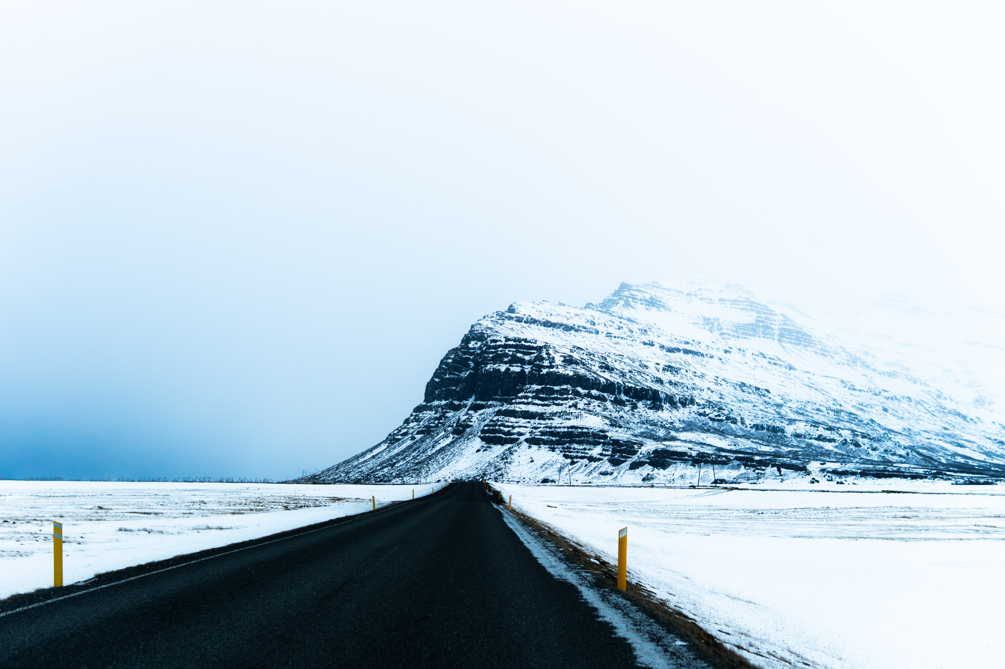 Nebelverhangener Berg auf einsamer Straße in Island